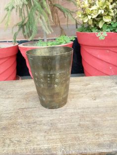 a small glass sitting on top of a wooden table next to potted planters