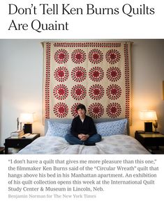 a woman sitting on top of a bed in front of a quilt