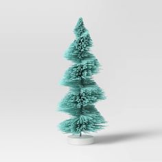 a small green christmas tree sitting on top of a white table