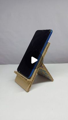 an open cell phone sitting on top of a wooden stand next to a white wall