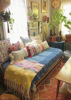 a living room filled with furniture and lots of plants on the windows sills