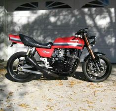 a red motorcycle parked in front of a garage