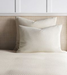 two white pillows sitting on top of a bed