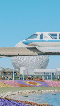 a monorail going over a flower garden in front of a building