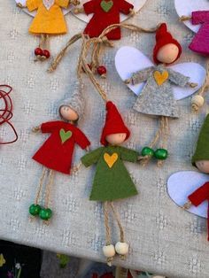 several small wooden elves are hanging from twine strings on a table with other decorations