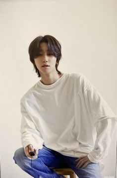 a young man sitting on top of a wooden stool