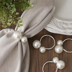 three pairs of pearl hoop earrings on top of a wooden floor next to a plant