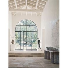 a large open room with an arched window and stone steps leading up to the front door