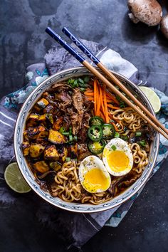 a bowl filled with noodles, eggs and vegetables next to chopsticks on the side