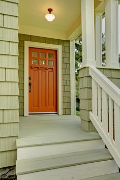 a red door is on the side of a house with white steps and railings