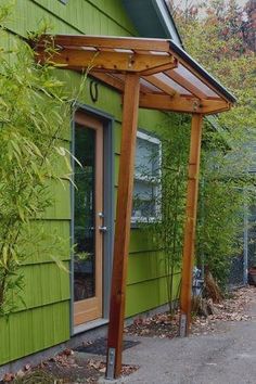 an outside view of a green house with a wooden pergolan attached to it