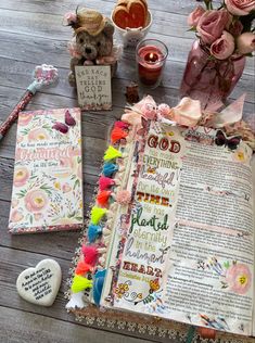 an open bible next to some flowers and other items on a wooden table with pink roses