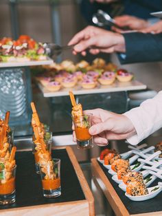 several people are serving themselves food at a buffet table with drinks and appetizers