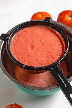 a pot filled with red liquid next to some oranges