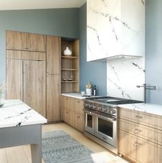 a kitchen with marble counter tops and wooden cabinets, along with stainless steel oven hoods