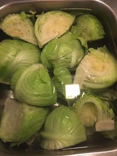 some cabbages are in a metal bowl on the counter