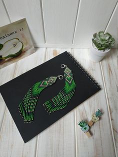 a book with some beads on it next to a cactus and succulents