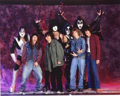 a group of people standing next to each other in front of a purple background with masks on