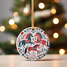 a christmas ornament with horses on it sitting in front of a christmas tree