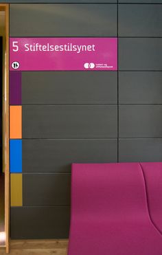 a pink chair sitting in front of a wall with different colored panels on it's sides