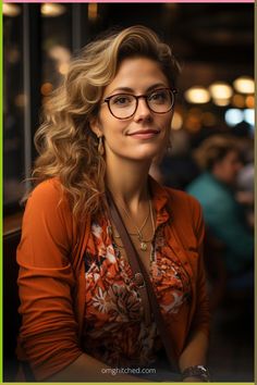 a woman wearing glasses sitting at a table with her arms crossed and smiling for the camera