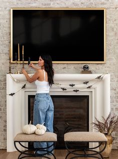 a woman standing in front of a fireplace holding candles