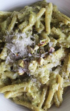 pasta with pesto and parmesan cheese in a white bowl