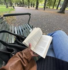 a person sitting on a park bench with an open book in their lap, reading