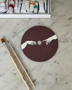 the creation of hands painted on a disc with paintbrushes next to it