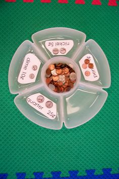 a plastic bowl filled with coins on top of a green table