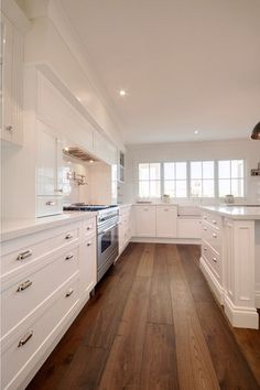 a kitchen with white cabinets and wood floors