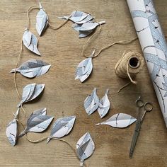 scissors, twine and paper leaves are sitting on a table next to a roll of string