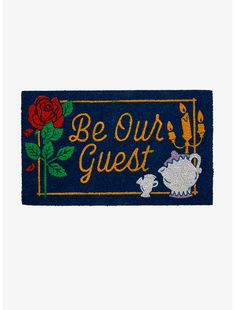 a blue door mat with the words be our guest and two teapots on it