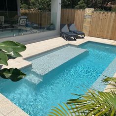 an empty swimming pool in the middle of a backyard with lounge chairs and plants around it