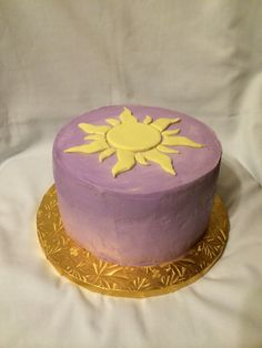 there is a purple cake with yellow decorations on the top and bottom, sitting on a gold plate