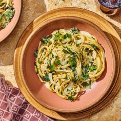 a plate of pasta with spinach and sauce on a table next to other dishes