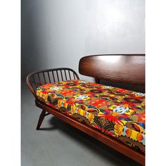 a bed with a wooden headboard and colorful bedspread on top of it