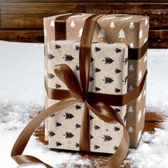 a wrapped present sitting in the snow with a brown ribbon on it's side