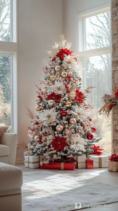 a white christmas tree with red and gold ornaments in a living room area next to a window