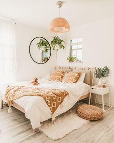 a bedroom with white walls and wooden flooring is decorated in neutral colors, including an orange bed spread