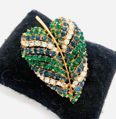 Beautiful vintage signed ART by Arthur Pepper green and clear rhinestone leaf brooch. Gold plated metal securely set with emerald green,sapphire blue and sparkling clear pave rhinestones in a leaf design. In excellent vintage condition with minimal age appropriate wear. Roll over clasp secure. Measures 2 3/8 inches tall by 1 5/8 inches wide. Jewelry Holders, Vintage Designer Jewelry, Leaf Brooch, Brooch Vintage, Green Sapphire, Star Art, Sapphire Blue, Vintage Designer, Stuffed Green Peppers