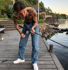 a woman with tattoos is fishing on the dock