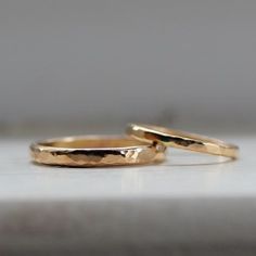 two gold wedding rings sitting on top of a white counter