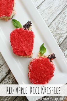 three red apple rice krispies on a white plate with green leaves and blackberries