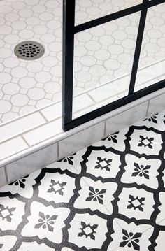 a bathroom with black and white tiles on the floor, shower door and toilet seat