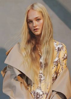 a woman with long blonde hair wearing a trench coat