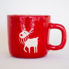 a red coffee cup with a white reindeer on it