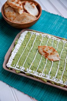 a green cake with white icing and a tortilla on the plate next to it