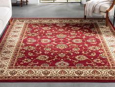 a large red rug with gold and white designs on it in a living room area