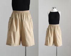 Vintage 80's high waist cargo shorts in beige. Elastic waistband. Long length. Loose fit. Unlined. Lightweight material. Waistband unstretched* - 26.5" --- 67.3 cm Hips** - 49.5" --- 125.8 cm Inseam - 7.5" --- 19 cm Outseam - 20" --- 51 cm Rise - 14.25" --- 36 cm Leg opening - 30" --- 76 cm Note *Since the waistband is elastic, it best fits someone who's waist is at least a few inches larger than 26.5". **Leave some wiggle room for your hips so you can move around comfortably, at least 3" or 7.5 cm. - Best fits 29" to 32" waists / modern size medium, check measurements. - Vintage size 18, check measurements. - 50% cotton, 50% polyester. - In excellent used vintage condition. - Handwash and air dry recommended for care. Garment pinned at waist. The mannequin's measurements are 33" - 25.5" - Cheap Beige Bottoms With Built-in Shorts, Vintage Cargo Bottoms For Summer, Vintage Summer Bottoms With Cargo Pockets, Vintage Bermuda Bottoms With Pockets, Vintage Bottoms With Side Pockets, Short Length, Vintage Knee-length Shorts With Pockets, Vintage Cargo Pocket Shorts For Summer, Vintage Short Bottoms With Cargo Pockets, Vintage Summer Cargo Shorts With Pockets